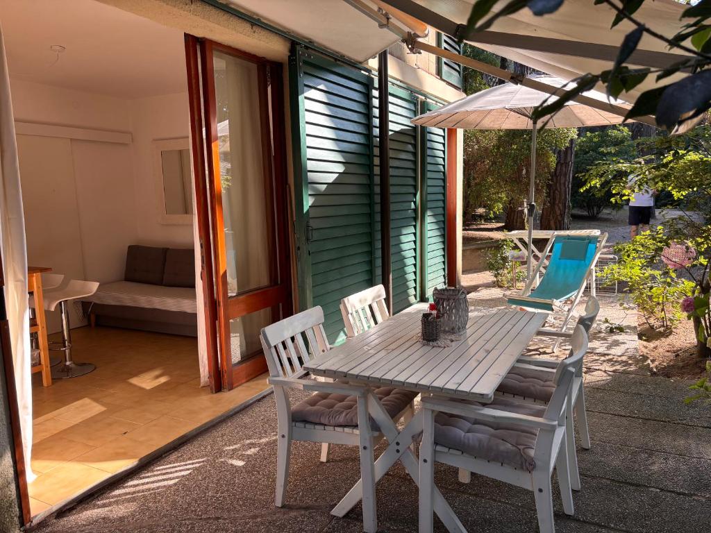 a wooden table with chairs and an umbrella on a patio at Home C 44 con posto spiaggia in Eraclea Mare