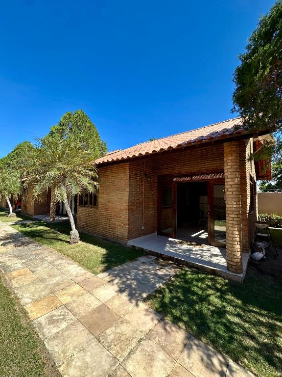 a brick house with a porch and a yard at Casa Praia do Frances in Marechal Deodoro