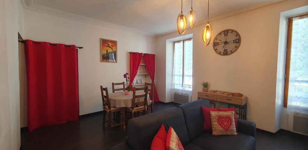 a living room with a couch and a clock on the wall at le galeta cosy calme et chaleureux avec vue sur la montagne in Aigueblanche
