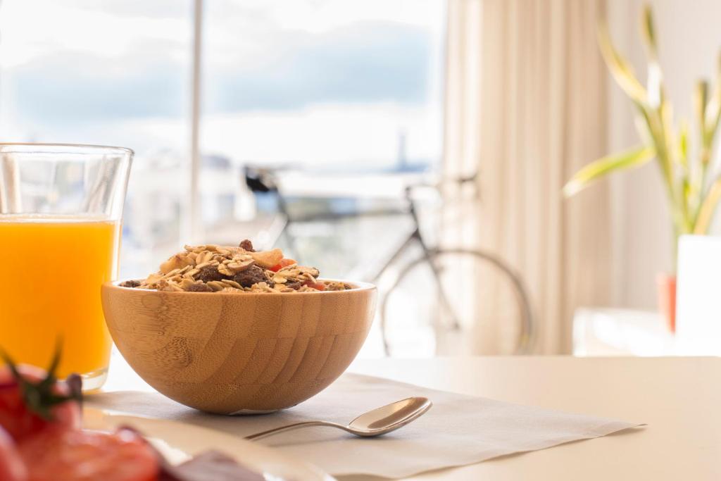 a bowl of cereal next to a glass of orange juice at Las Gaviotas Suites Hotel & Spa in Playa de Muro