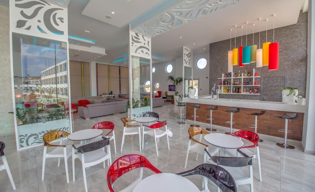 a restaurant with white tables and red chairs at Nicholas Color Hotel in Ayia Napa