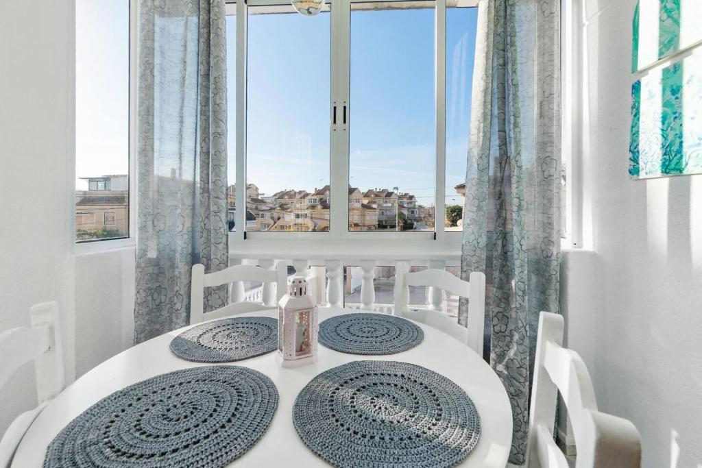 a dining room with a table and chairs and a window at Acogedor bungalow de primera planta en Torreblanca in Torrevieja