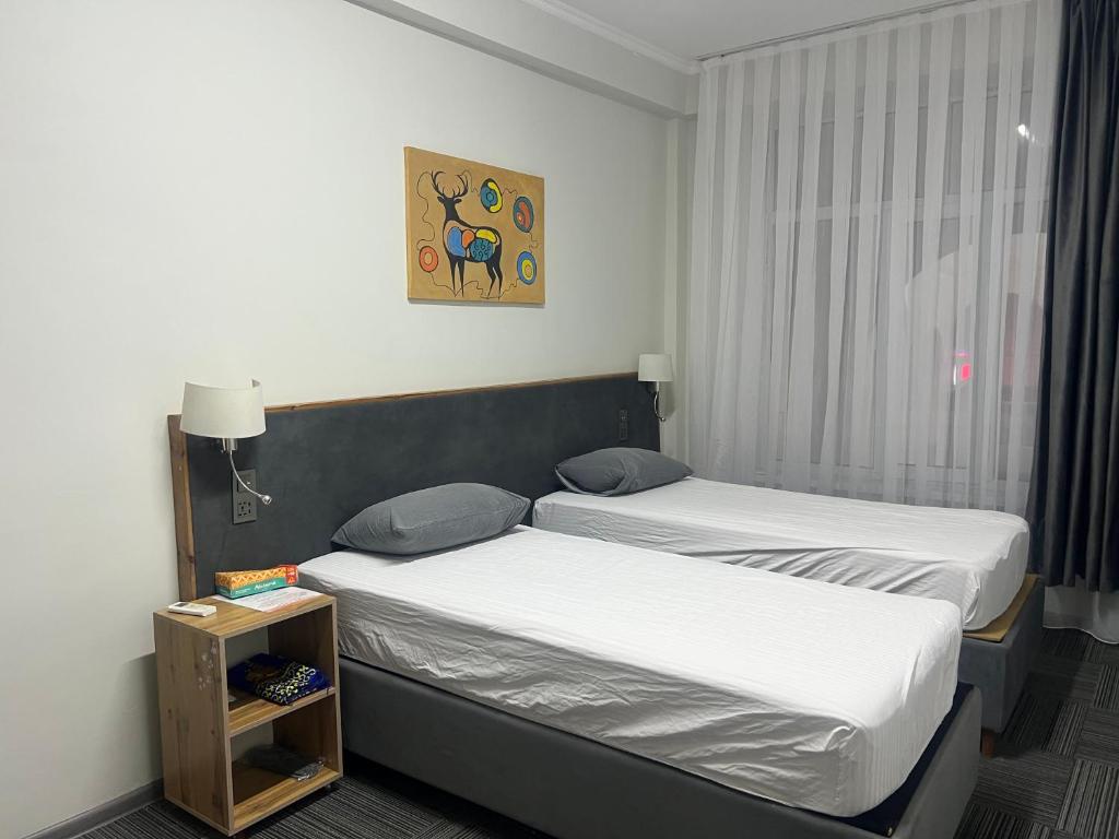 a room with two beds and a picture on the wall at OSH ART Meergul in Osh