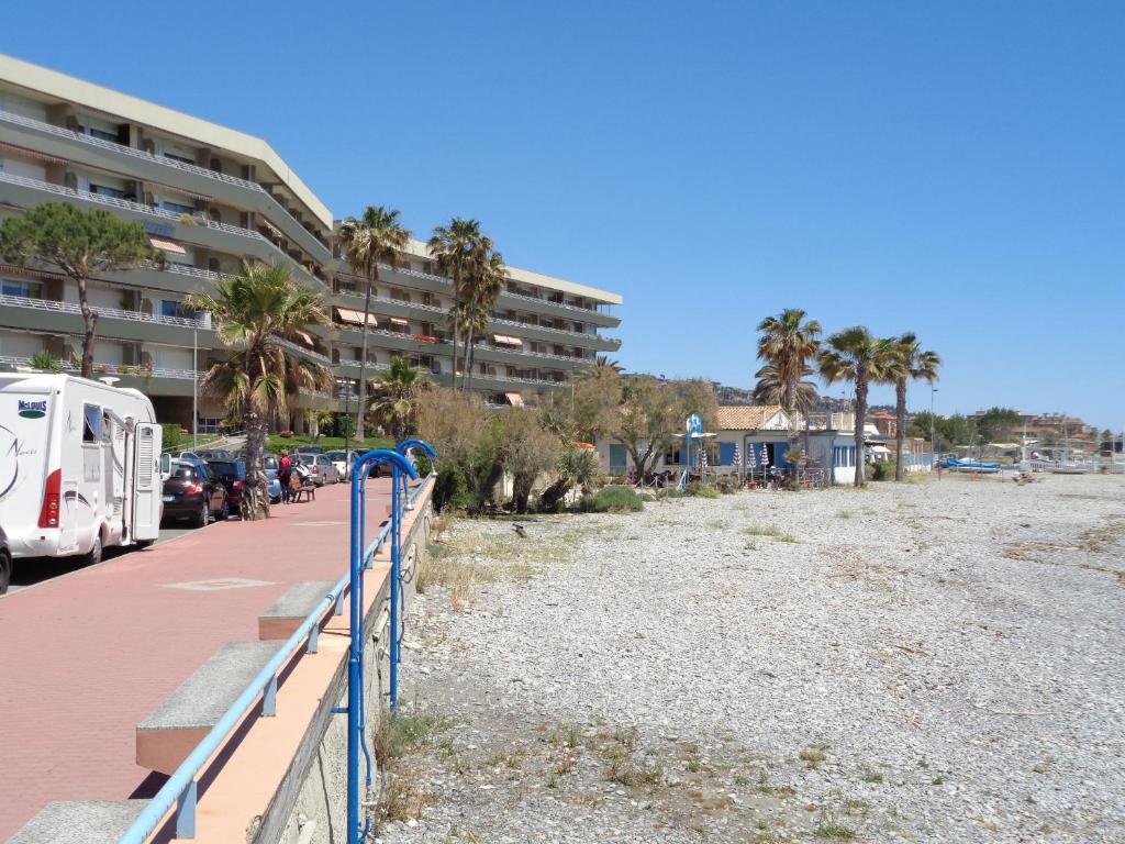 uma vista para uma praia com palmeiras e um edifício em appartamento sul mare Massasso em Ventimiglia