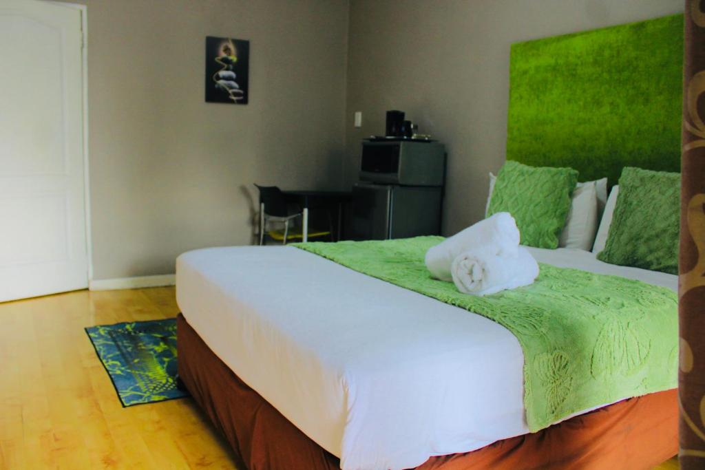 a bedroom with a large white bed with a green blanket at Cockpit Guest House Kempton Park Airport Getaway in Kempton Park