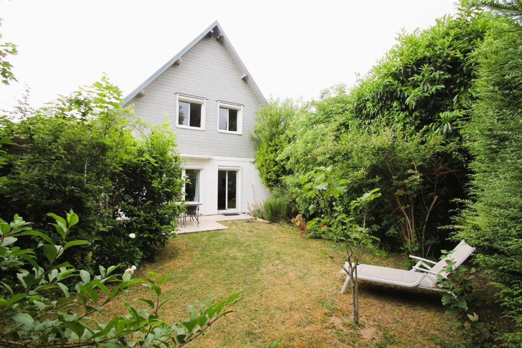 a white house with a bench in the yard at Le Jardin Champenois Maison in Tinqueux