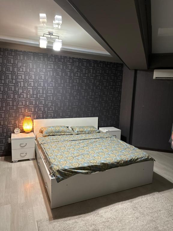 a bedroom with a bed and a lamp on a table at Квартира в центре in Bishkek