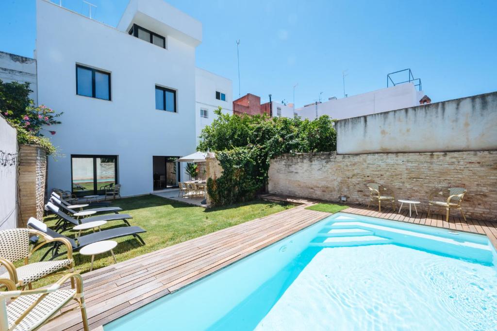 Una piscina con tumbonas al lado de un edificio. en Al Sur Home Marqués, en Sevilla