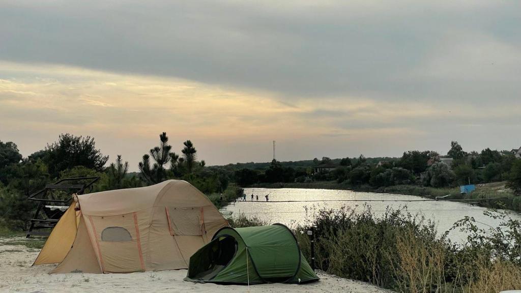 Una tienda de campaña situada en la arena junto a un río. en Кемпінг, намети, en Surskoye