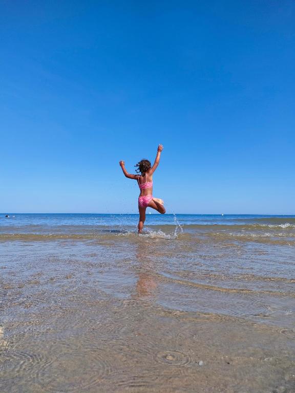 a woman jumping in the water on the beach at Sunset Spot à Bredene in Bredene