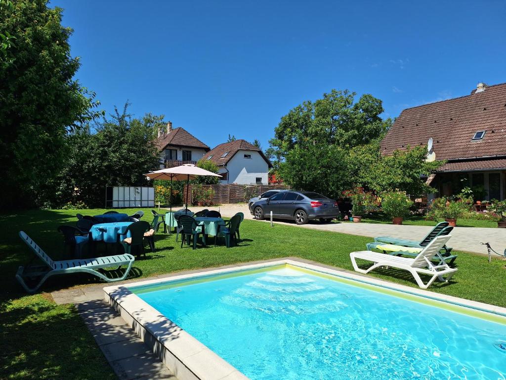 a swimming pool in a yard with chairs and tables at Margaréta Apartman - Balatonlelle in Balatonlelle