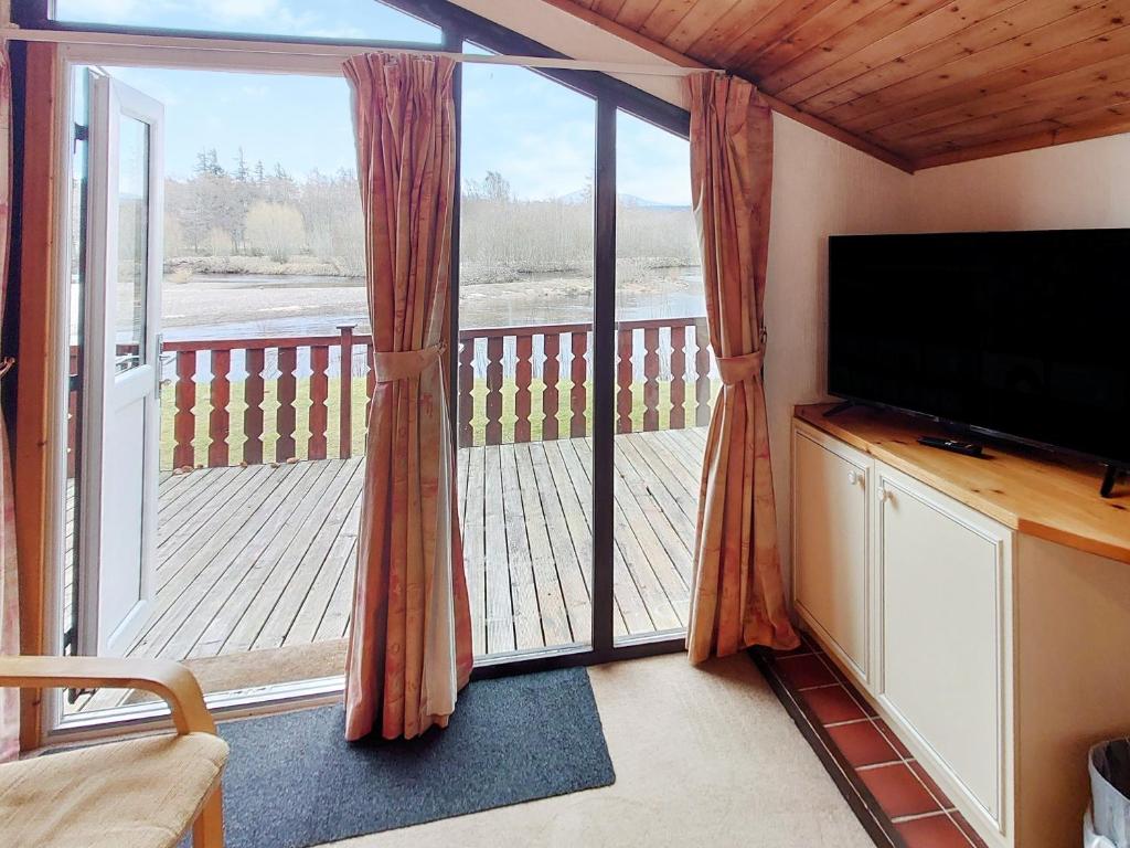 sala de estar con TV y porche acristalado en 27 Aviemore Holiday Park, en Aviemore