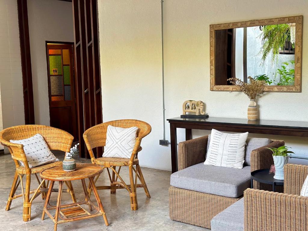 A bright lounge with wicker seating, cushions, a console, and a garden-facing mirror.