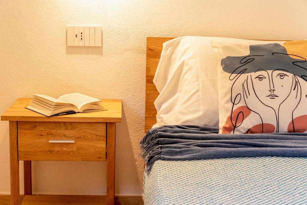 サン・テオドーロにあるMaison Apartments San Teodoro Centerのナイトスタンドに本が置かれたベッド、その隣には本が置かれたベッド