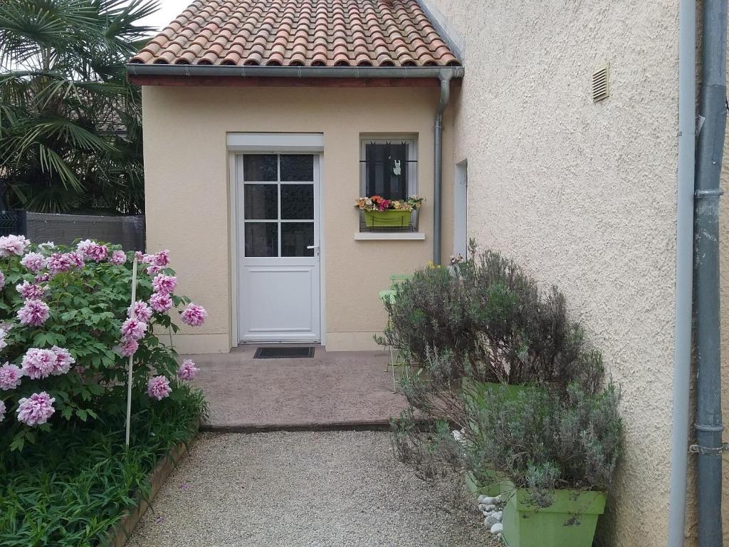 a house with a white door and a window and flowers at gîte La Valentina, climatisé in Cubjac-Auvézère-Val d'Ans