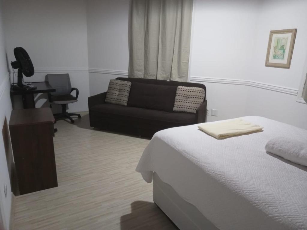 a bedroom with a bed and a chair and a couch at Uma casinha rosa no Pacaembu in Sao Paulo