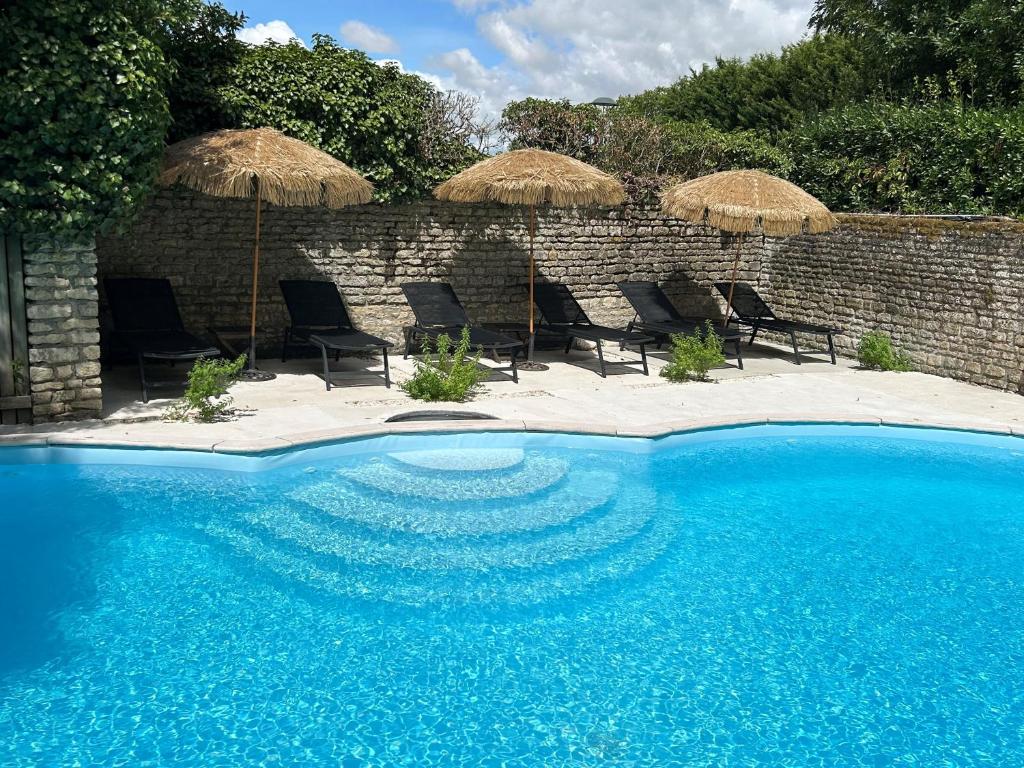 une grande piscine bleue avec chaises et parasols dans l'établissement Château de l'Abbaye - Teritoria, à Moreilles