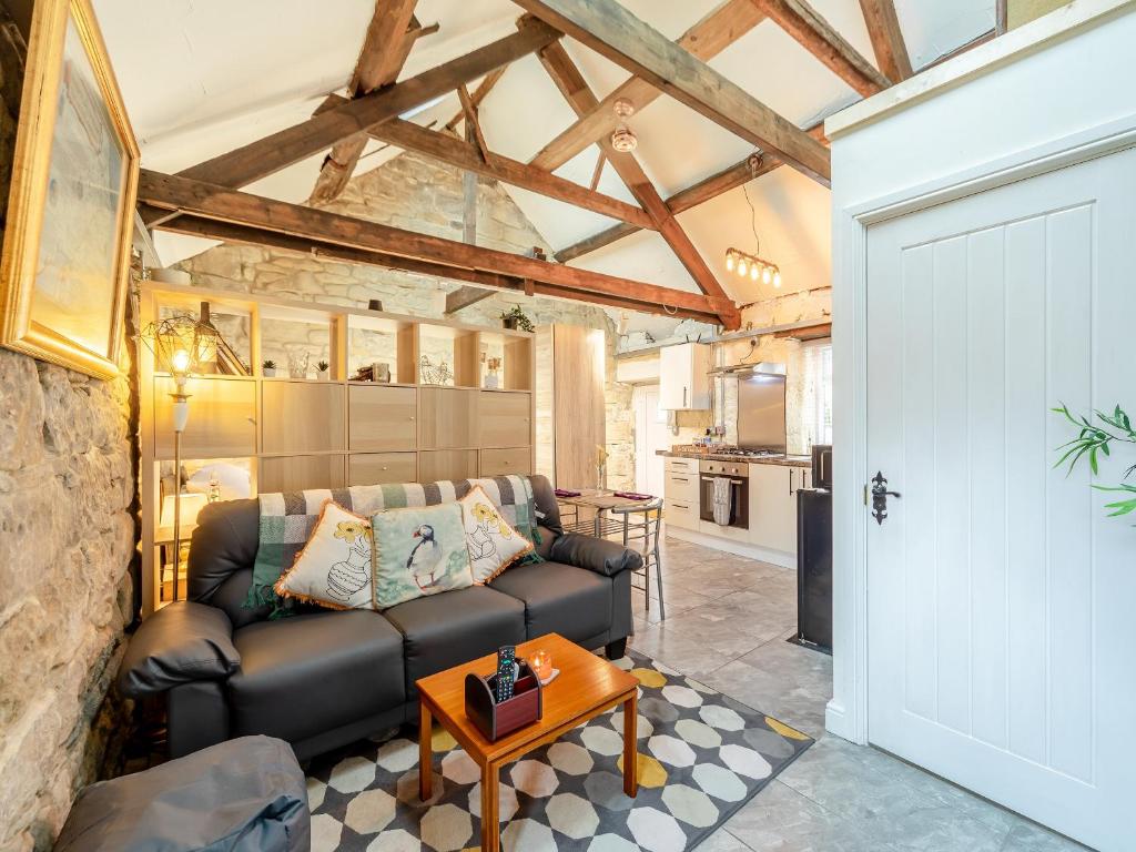 a living room with a leather couch and a table at The Old Wash House in Amble