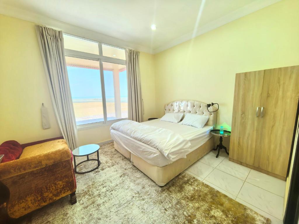 a bedroom with a bed and a large window at NatureLand Beach Villa in Al Mughayrāʼ