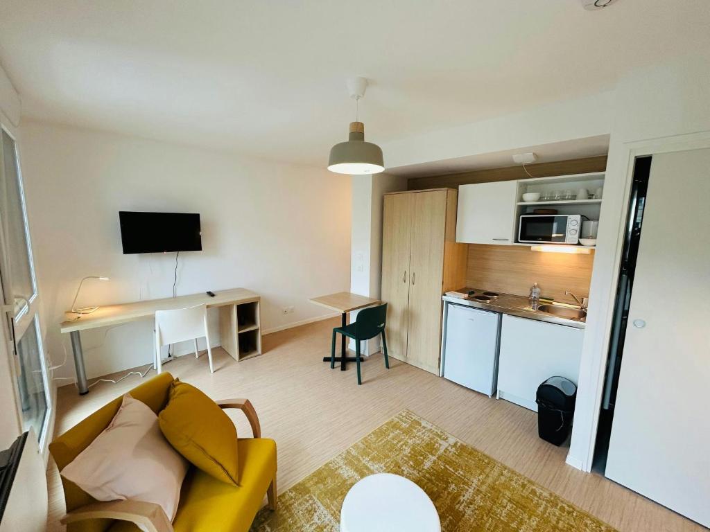 un salon avec un canapé jaune et une cuisine dans l'établissement We Live In R - Suite 202, à Reims
