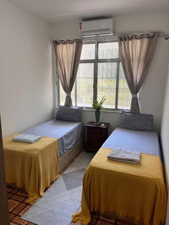 two beds in a room with a window at Colinna Hostel in Rio de Janeiro