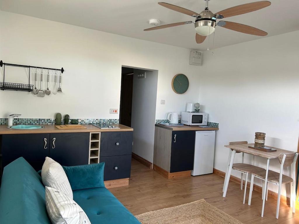 un salon avec un canapé bleu et une cuisine dans l'établissement The Cosy Cabin, à Pembrokeshire