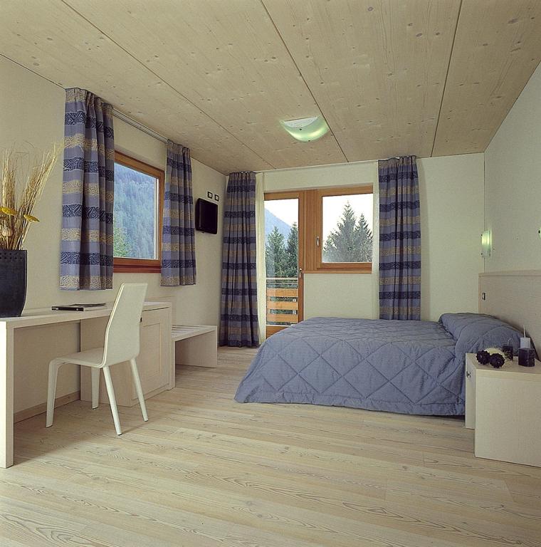 sypialnia z łóżkiem, biurkiem i oknami w obiekcie Bio Hotel Benny w mieście Commezzadura