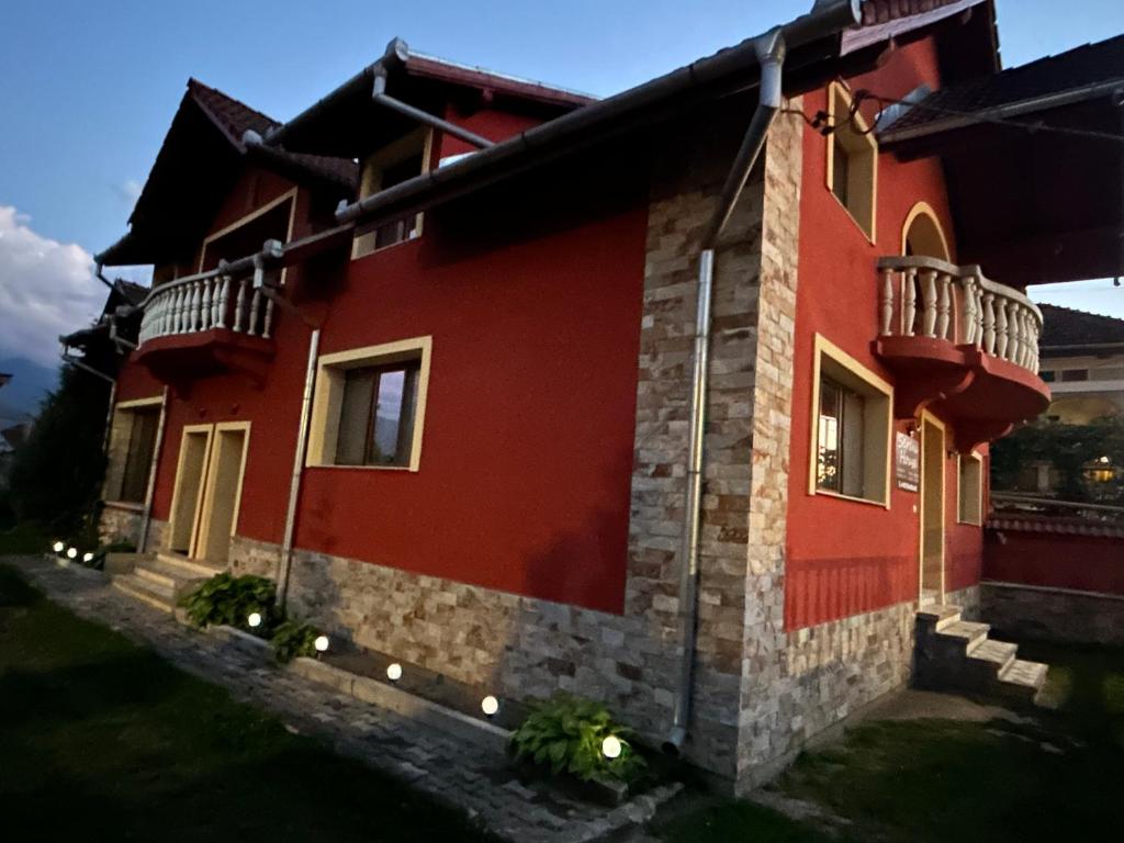 a red house with lights on the side of it at Serena House in Cîrţişoara