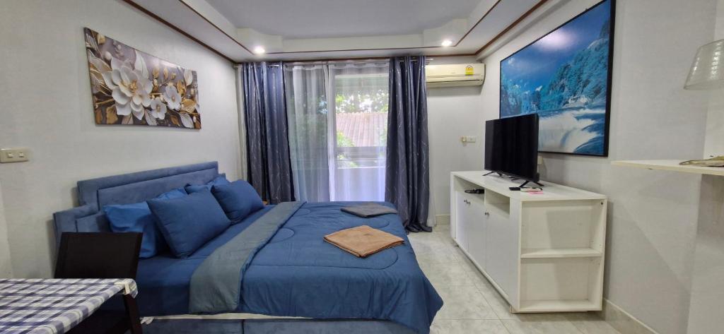 a bedroom with a blue bed and a television at Rawai Condotel 3 in Rawai Beach