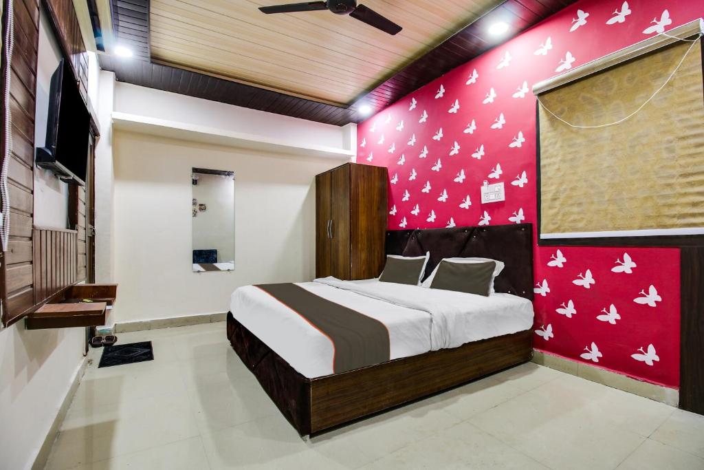 a bedroom with a bed and a pink wall at Super Hotel O Sawariya Regency in Bhopal
