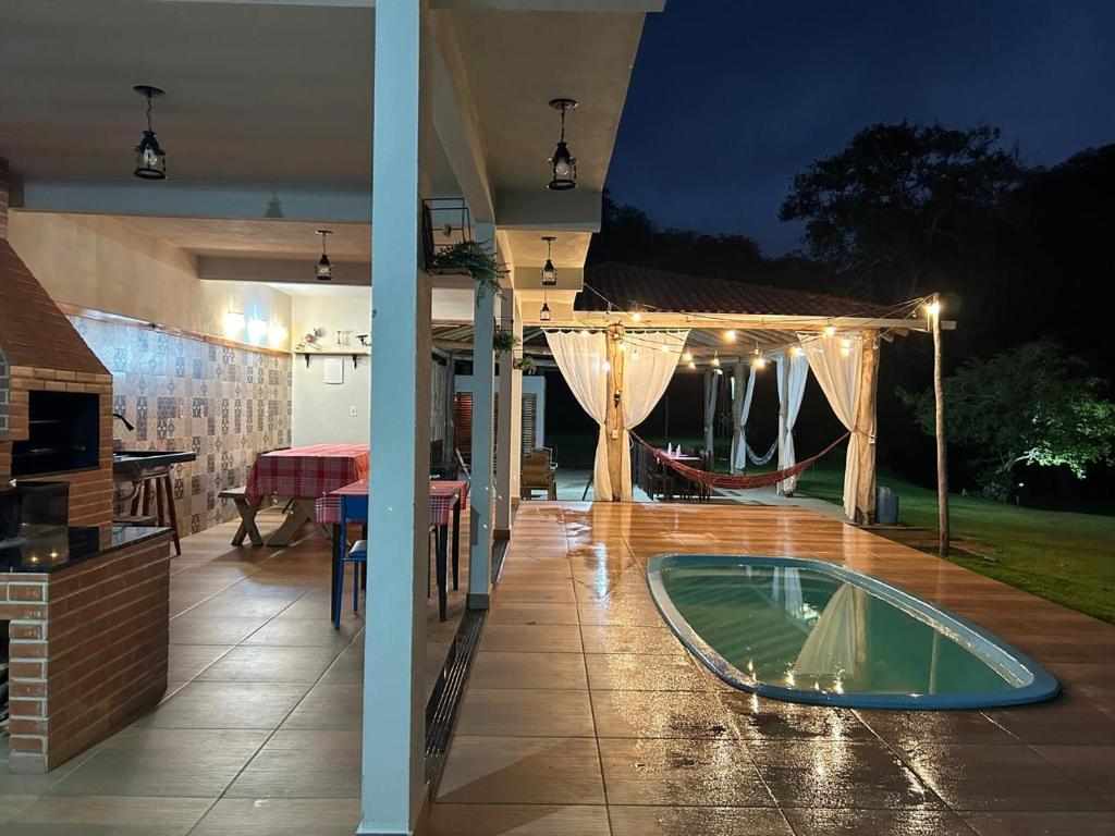 eine Terrasse mit einem Tisch und einem Pool in der Nacht in der Unterkunft Sítio Cantinho da Roça Perobas in Paraju