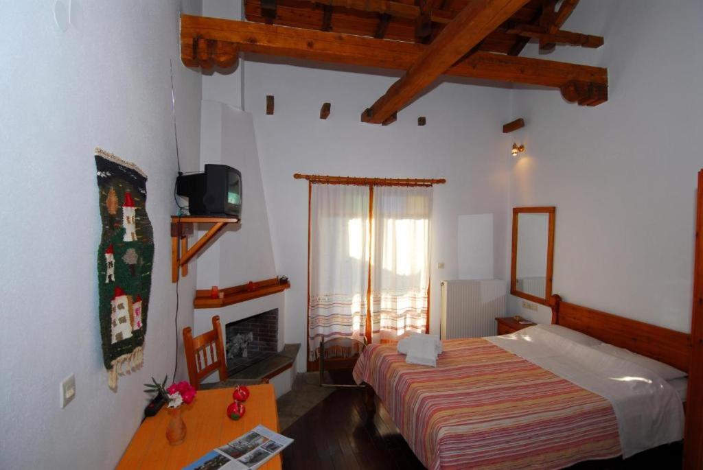 a bedroom with a bed and a tv and a fireplace at Guesthouse Apanemia in Afissos