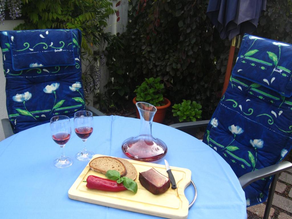 een tafel met een bord eten en twee glazen wijn bij Haus am Südfrüchtegarten in Rhodt unter Rietburg