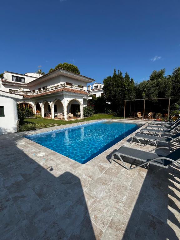 a swimming pool with lounge chairs in front of a house at Villa Allyson Boutique Guesthouse in Lloret de Mar
