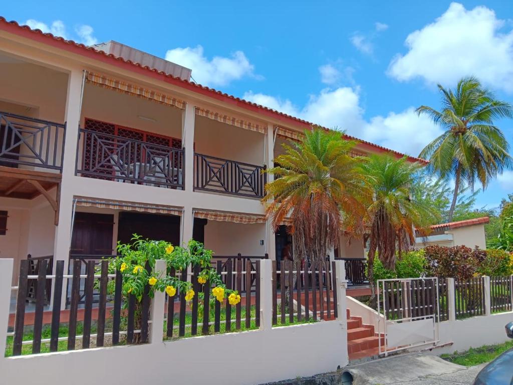 una casa con recinzione e palme di Les coraux arc en ciel Résidence CORAUX F2 meublé à 300m de la plage à Saint Anne a Sainte-Anne