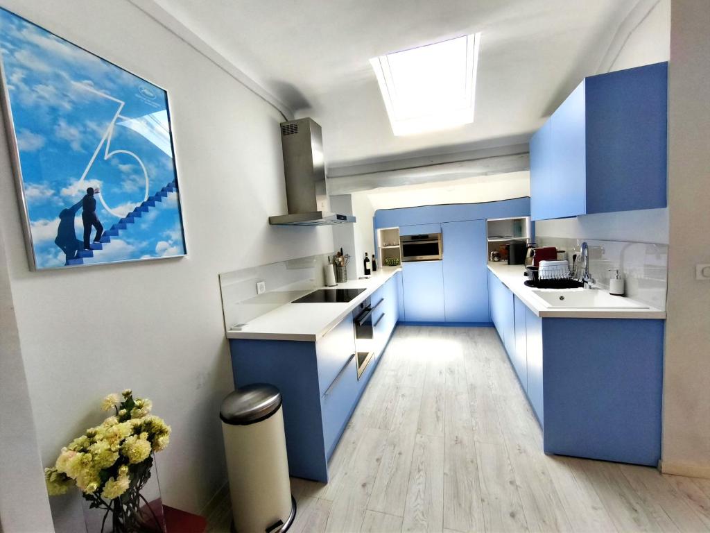 a kitchen with blue cabinets and a painting on the wall at Location vacances T3 à Cannes in Cannes