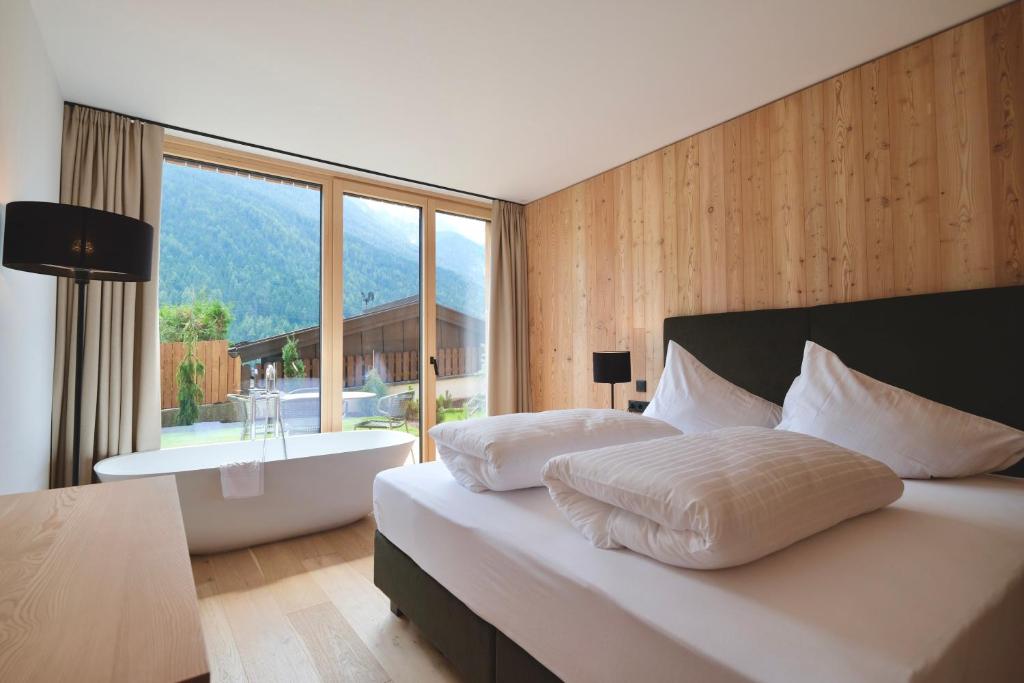a bedroom with a bed with a bath tub and a window at Lärchenlodge SkySpa and Rooftop Pool inklusive Stubai SuperCard in Fulpmes