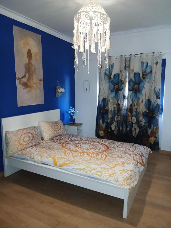 a bedroom with a bed with blue walls and a chandelier at Macarena-AL in Almada