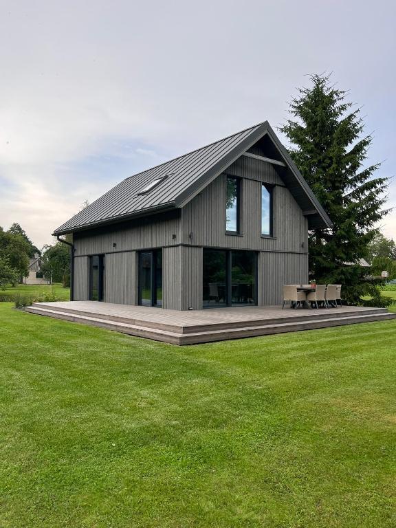 a large gray building with a picnic table in a field at Bernātu Kalnmaļi in Bernāti