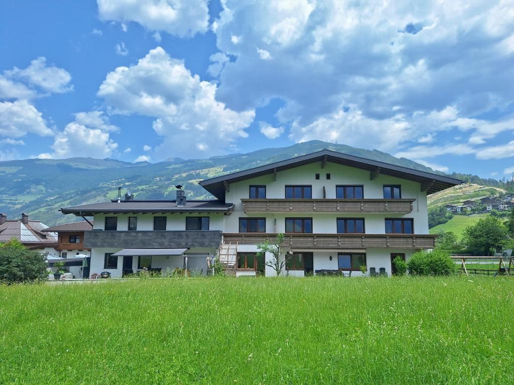 a large building with a green field in front of it at Alpenzeit Zillertal Apartments in Zell am Ziller