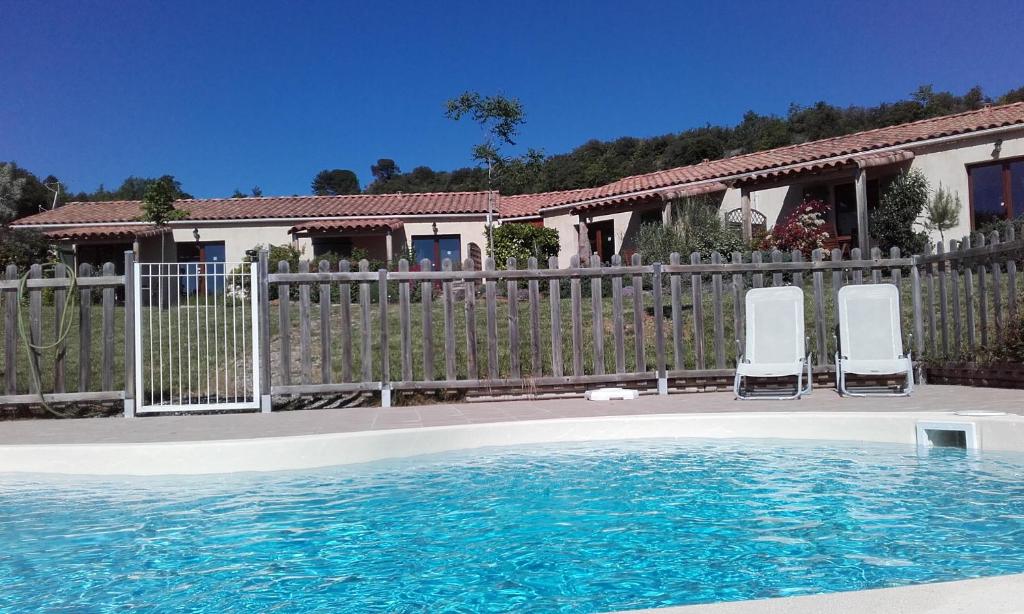 una piscina con 2 sillas y una valla en gîtes "Entre les Vignes", en Tourreilles