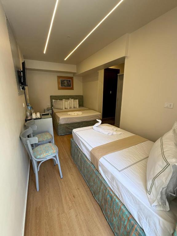 a hotel room with two beds and a chair at Ambiance Hotel in Cairo