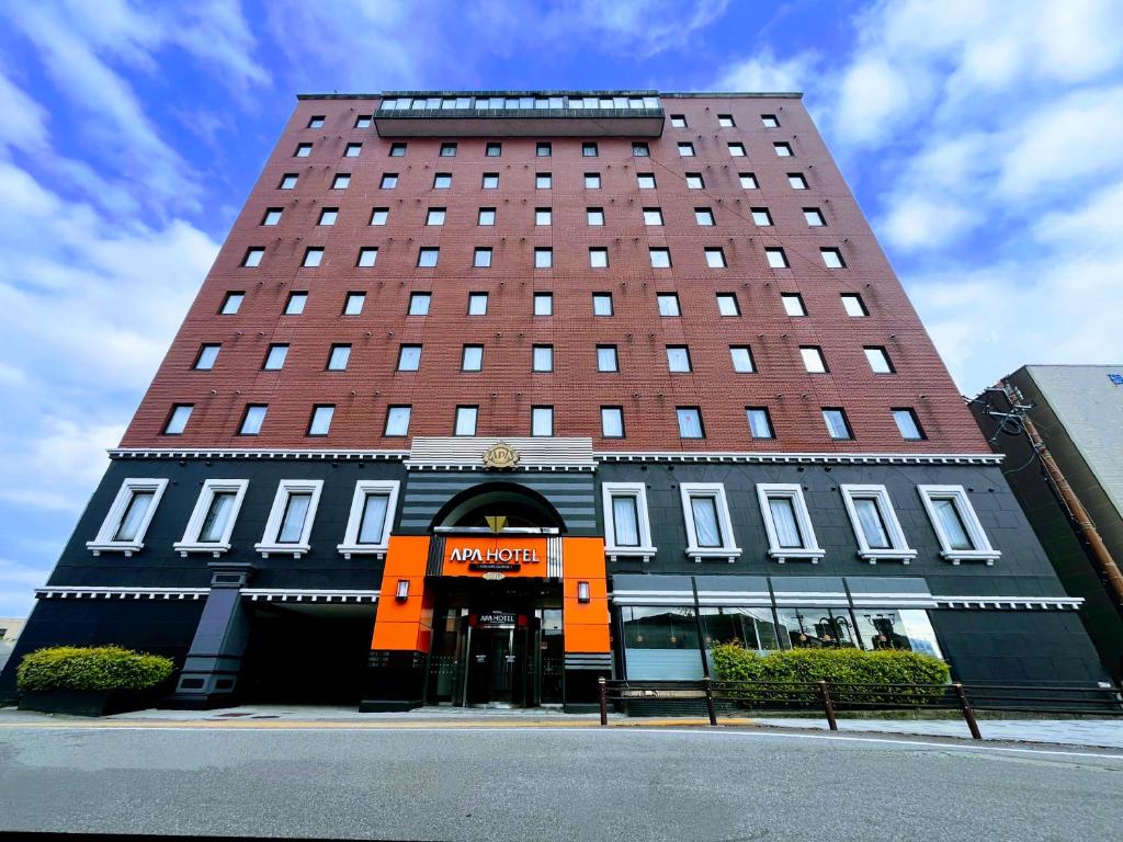 a tall red building with a m hotel at APA Hotel Tonami Ekimae in Tonami