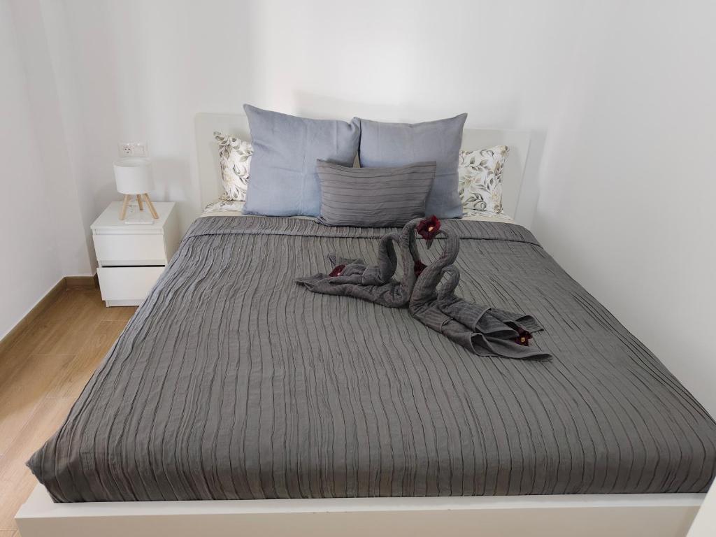 a bed with a gray comforter with a doll on it at Piedras del Teide in Guía de Isora