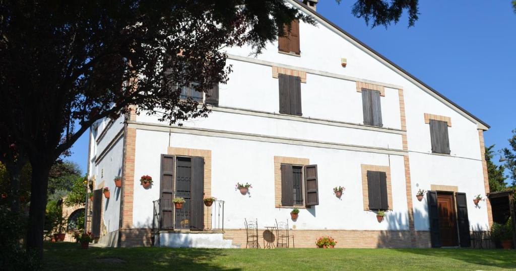 an old white building with windows and a tree at Antico Casale Fossacieca in Civitanova Marche