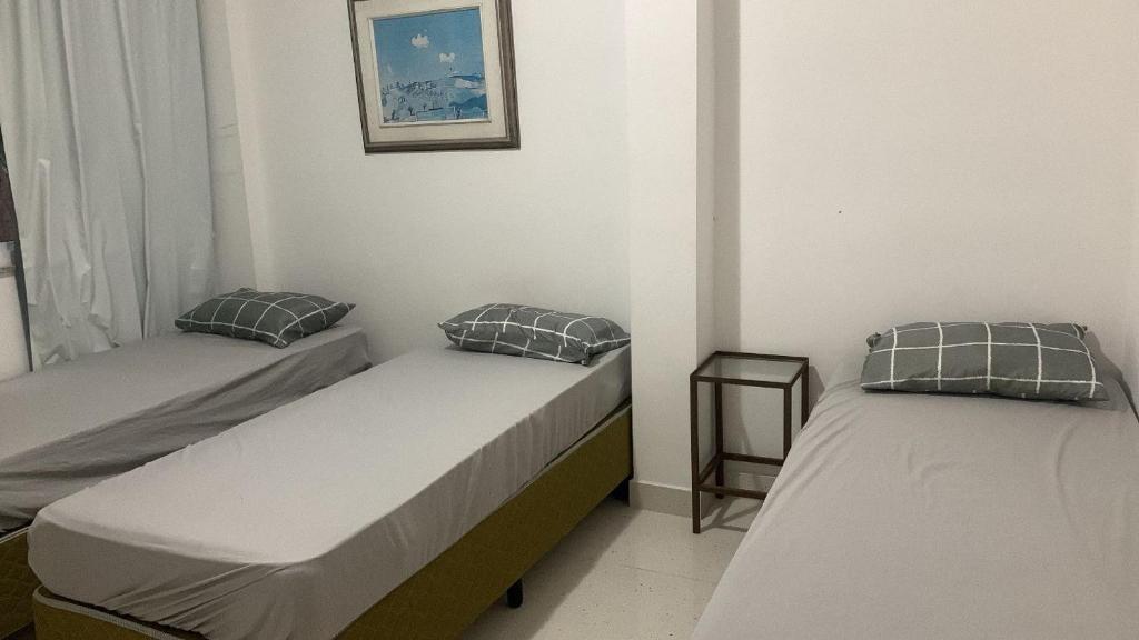 a room with two beds in a room with a window at Apartamento refúgio tropical in Arraial do Cabo