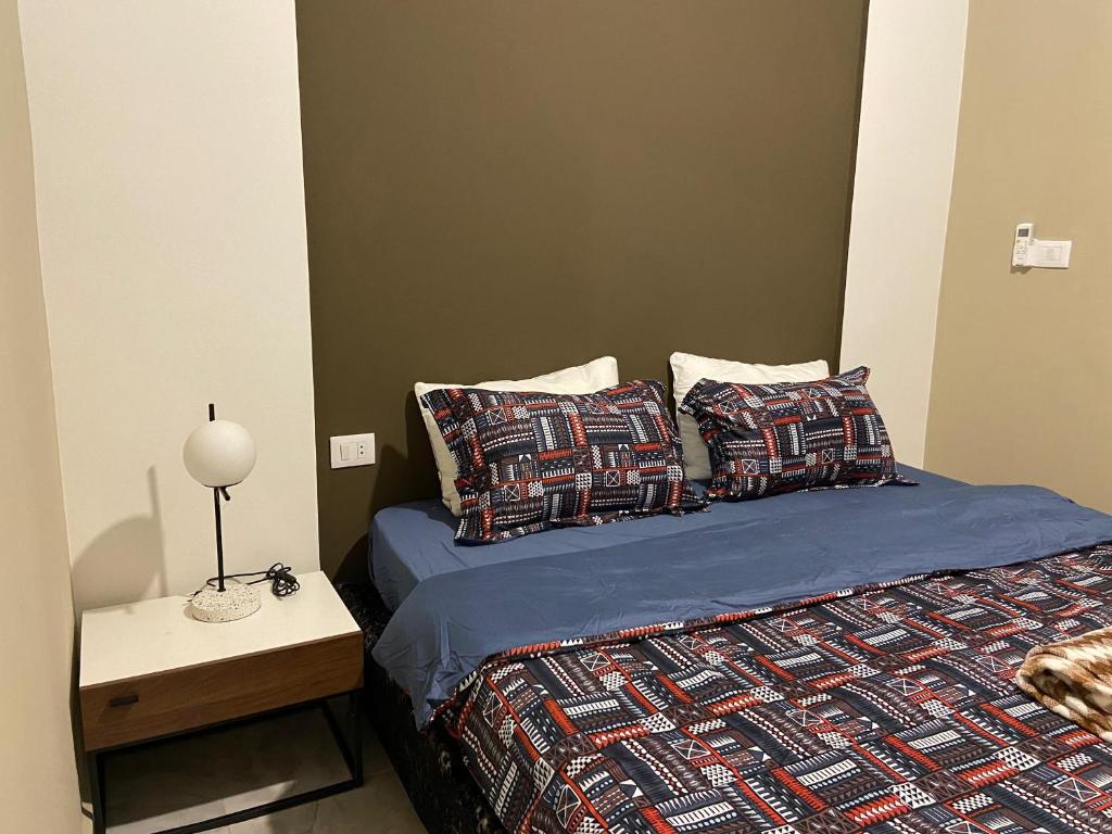 a bed with a blue comforter and pillows in a room at Cosy, accessible, comme et sécure in Kinshasa