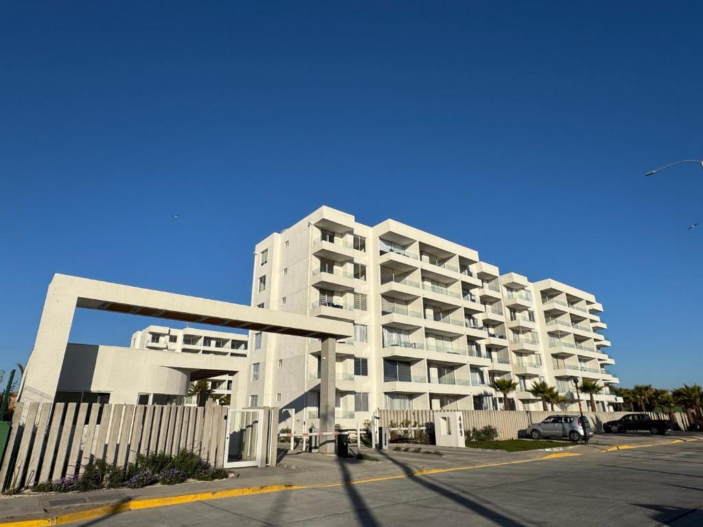 un gran edificio de apartamentos blanco con aparcamiento en Home Studio La Serena, en La Serena