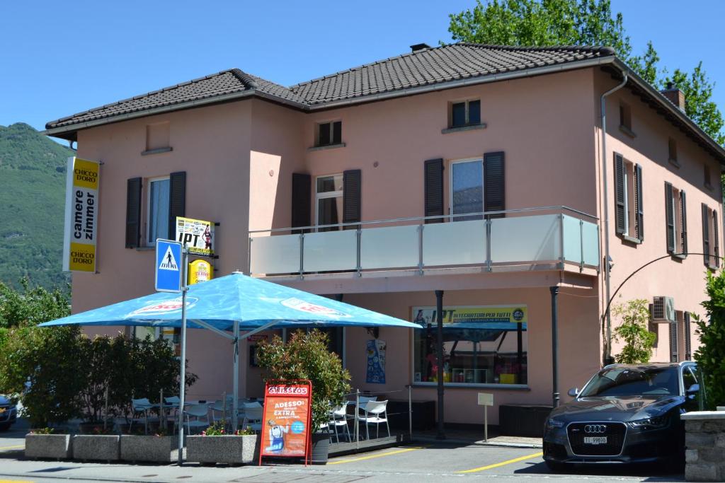 un edificio con un paraguas azul delante de él en Osteria Centrale, en Cadenazzo