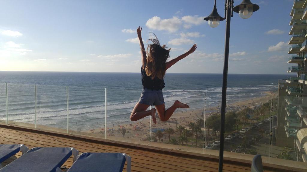 Una ragazza che salta in aria davanti alla spiaggia di Penthouse Apartment On The Beach a Bat Yam